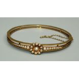 An Edwardian seed pearl and unmarked yellow metal bangle, comprising a floral cluster set with