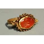 A Roman style gold and carnelian Ring, the raised cup setting with double border of granules and set