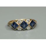A sapphire and diamond 18ct gold ring, comprising three square cut sapphires rub over mille grain