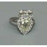 A diamond set heart shaped bow top ring, comprising a central pear cut very light yellow diamond