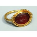 A Roman style gold and carnelian Ring, the thin hoop having oval bezel with granulated border, inset