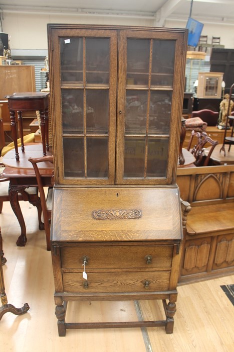 An early 20th Century oak bureau bookcase, fitted with two doors enclosing wooden shelves, the