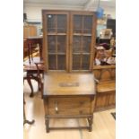 An early 20th Century oak bureau bookcase, fitted with two doors enclosing wooden shelves, the