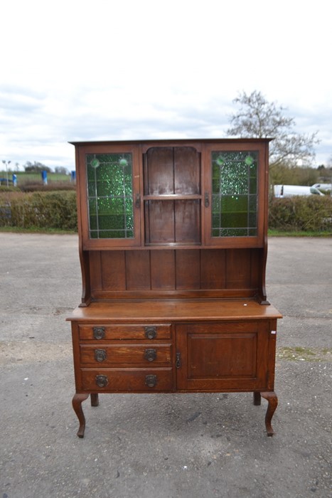 An Art Nouveau oak sideboard, circa 1910, with glazed upper section fitted with stained glass doors,