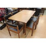 A 1970s teak dining table and a set of six chairs, the table having a fold-out leaf, measuring