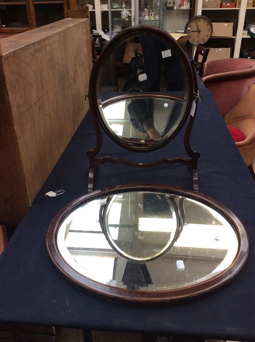 An Edwardian style stained wood oval shaped dressing table mirror and an oval wall mirror (2)