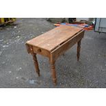 A 20th Century pine drop leaf table, measuring 75cm high, 100cm wide, 56cm deep