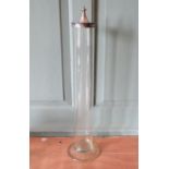 A tall glass cylinder with white metal decorative lid. 62 cm tall.
