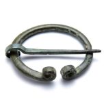 Iron Age penannular brooch. A late Iron Age to early Roman bronze penannular brooch with coiled