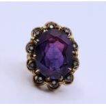 A yellow gold ring, claw set large purple oval and stone (possibly synthetic sapphire)