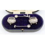 A pair of early 20th Century Asian silver (800 standard) circular salts, profusely engraved on bun