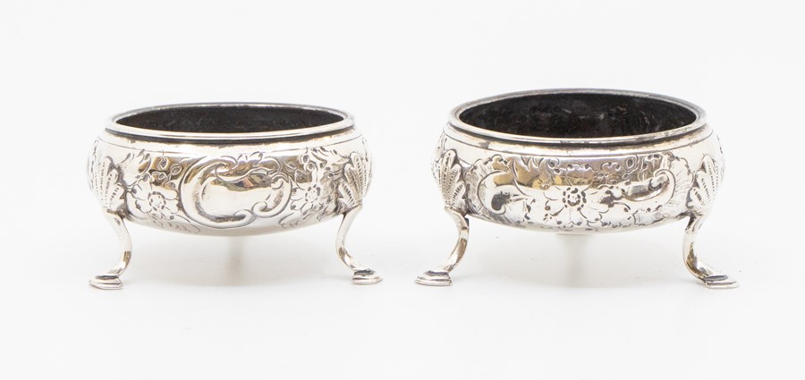 A pair of George III silver circular salts, the bodies chased with floral decoration and vacant