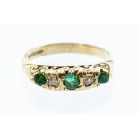 An emerald and diamond 9ct gold boat head ring, comprising three graduated round cut emeralds with