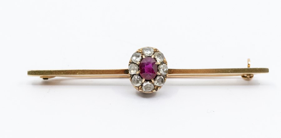 An Edwardian  ruby and diamond set 15ct gold bar brooch, comprising a central claw set oval ruby