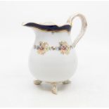 A Meissen cream jug with floral decoration, simulated tree branch decoration to feet and handle,