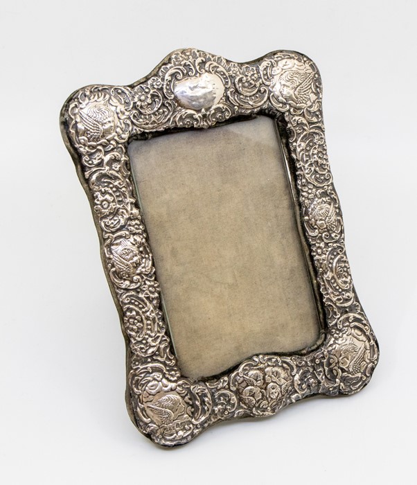 An Edwardian ornate silver photograph frame with embossed decoration featuring Reynolds angels' size