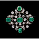 A diamond and emerald openwork lozenge shape Brooch/Pendant, comprising a rubover set central