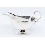 A George V silver sauce boat with scroll handle, hallmarked by William Hutton & Sons, Sheffield