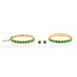 A pair of emerald and high carat yellow gold hinged bracelets, each claw set twelve round faceted