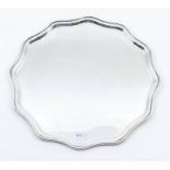 A George V silver shaped tray, plain floral shaped on thee stud feet, hallmarked by Boardman,