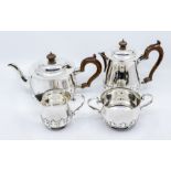 A George V silver four piece tea service with stylized leafage raised frieze, turned wooden scroll