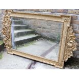 George II style giltwood and gesso mirror with a scrolling crest and winged cherub;s head apron