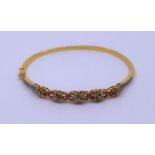 An Indian 19k yellow gold bracelet with fire graduated flower head cluster to the pierced front, set