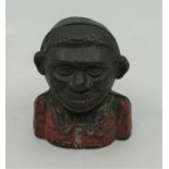 An early 20th century novelty money box, in the form of a black child, 11.5cm high