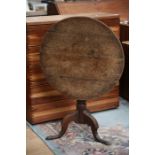 A George III Oak tilt-top tripod table, the circular plank top raised on a turned column, raised