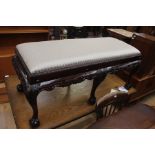 A contemporary mahogany effect long stool, in the George II style, machine carved frame, raised on