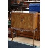 A mid 20th Century walnut cocktail cabinet, fitted with two doors enclosing a fitted interior,