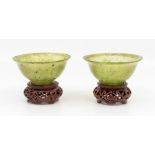 A pair of Asian green nephrite plain bowls on hardwood stands (2) .