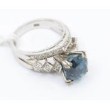 A sapphire and diamond and white metal cluster ring, high claw setting with a deep round cut