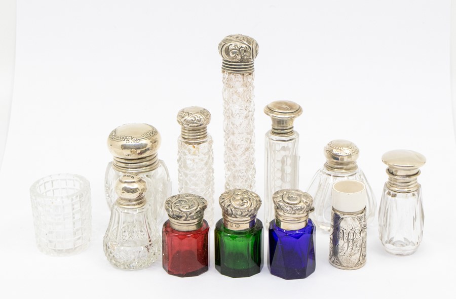 A collection of silver mounted cut & facet cut scent / toilet bottles, various dates and makers (