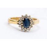 A sapphire and diamond cluster ring, comprising an oval claw set sapphire with diamond set border,