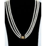 A cultured pearl necklace comprising three rows of button shaped white pearls, size approx. 4.6mm,