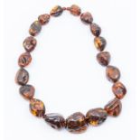 A dark brown amber bead necklace of irregular graduated form, the largest approx. 40 x 30 (large