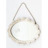 A Morrocan silver wedding mirror, the back elaborately embossed, with a blue enamelled centre,