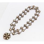 An early 20th century black oyster shall and white metal necklace, comprising a double row of