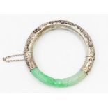 A Chinese jade and white metal bangle comprising carved jade with dragon decoration, with white
