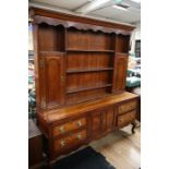 A George III style oak dresser with rack, circa 1920, the rack with two cupboard doors and