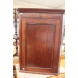 A George III mahogany corner cupboard, having a single door enclosing shelves, 95cm high, 70cm wide