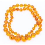 An amber bead necklace, comprising graduated round beads, the largest approx. 20mm, smallest approx.