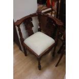 Mid 20th century reproduction mahogany corner library chair with padded seat and heavily carved.