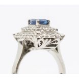 A sapphire and diamond white metal cluster ring, comprising a cushion shaped claw set sapphire,