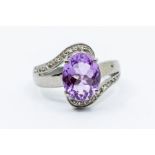 An amethyst and diamond silver dress ring, comprising a claw set oval cut amethyst set to the