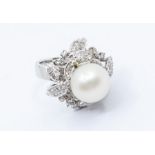 A cultured pearl and diamond white metal cluster ring comprising a round white cultured pearl with