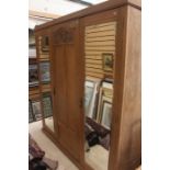 An Arts and Crafts oak triple sectioned wardrobe, mirrored doors to each side, central panelled