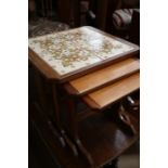 A nest of three G plan teak tables, the top largest table inset with four floral pattern tiles, with