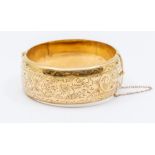 A 9ct gold hollow bangle, engraved decoration, width approx 25mm, dents to areas, weight approx 32